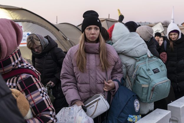 Nuori ukrainalainen nainen seisoo pakolaisleirillä matkatavarat kädessä.